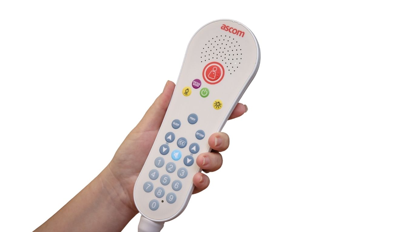 A side view of a person's hand holding the pillow speaker set against a white background. 
